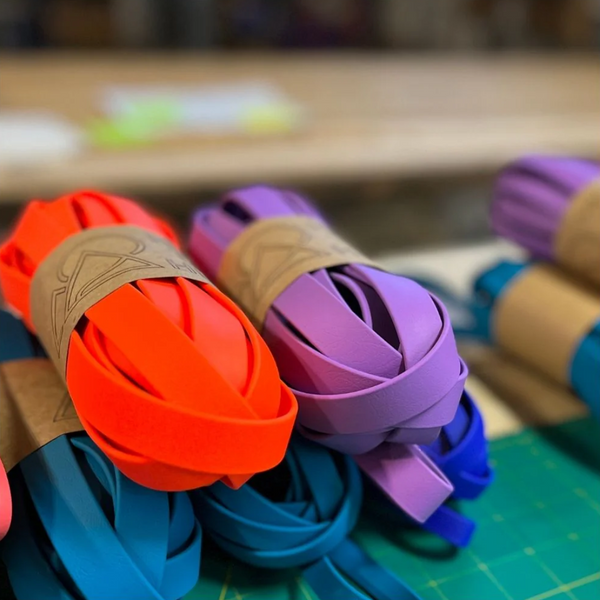 several biothane long lines coiled and wrapped with a tan high tail hikes bellyband laying on a workbench