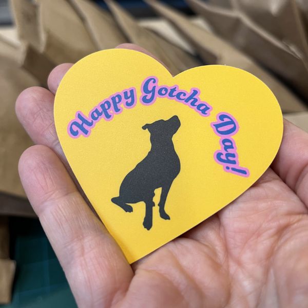 Yellow heart Happy Gotcha Day sticker w/ black dog on persons hand