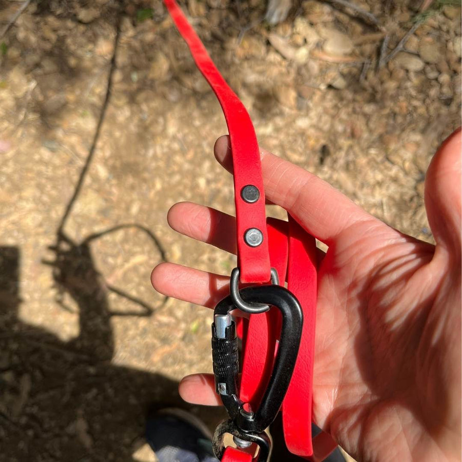 red sport biothane leash extender attached to a red leash in a persons hand
