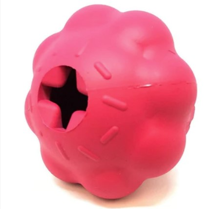 Pink rubber treat dispenser on its left side showing the hole on the top