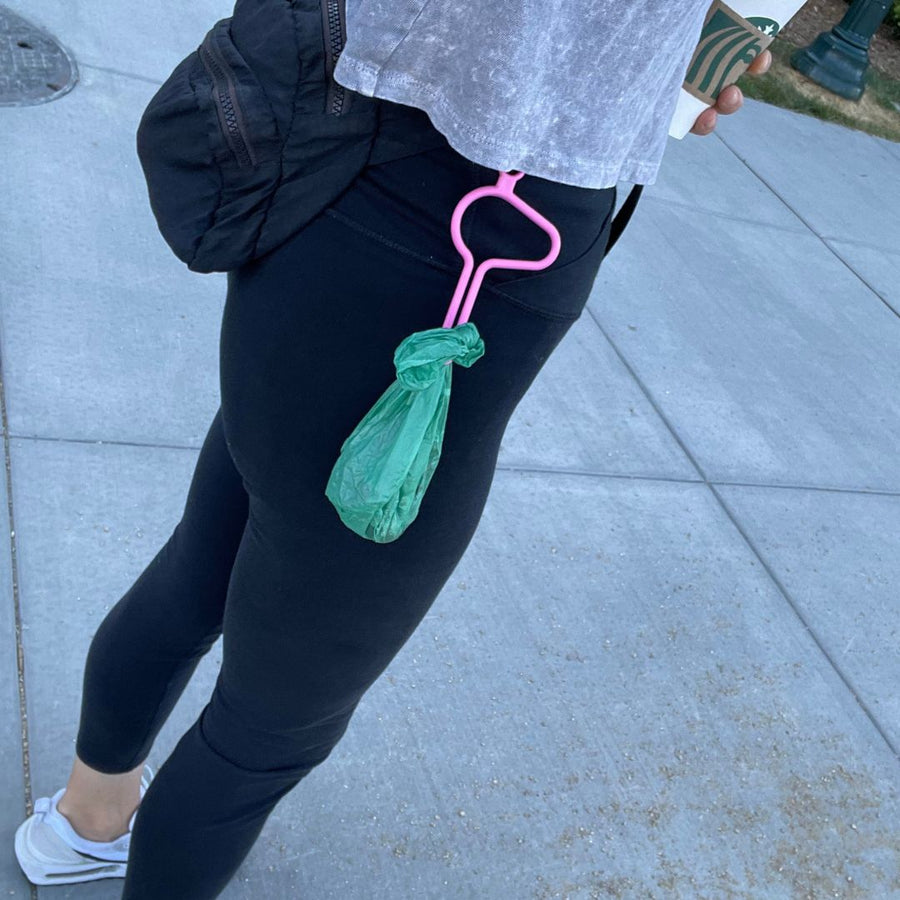 person wearing a pink dooloop dog waste bag holder on their belt
