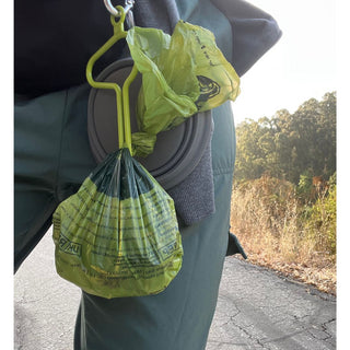 close up of person using the dooloop dog waste bag holder on their belt