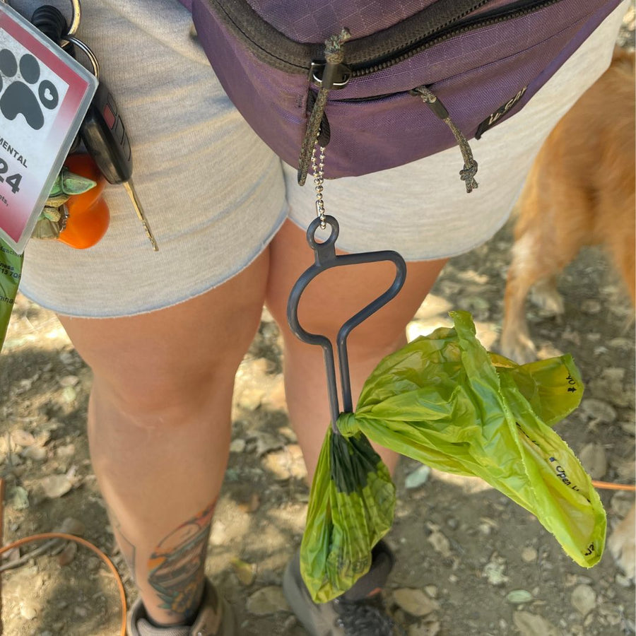 close up of person using the dooloop dog waste bag holder on their belt