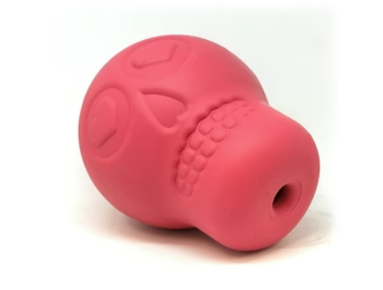 Large pink skull chewable dog toy and treat dispenser showing the bottom opening