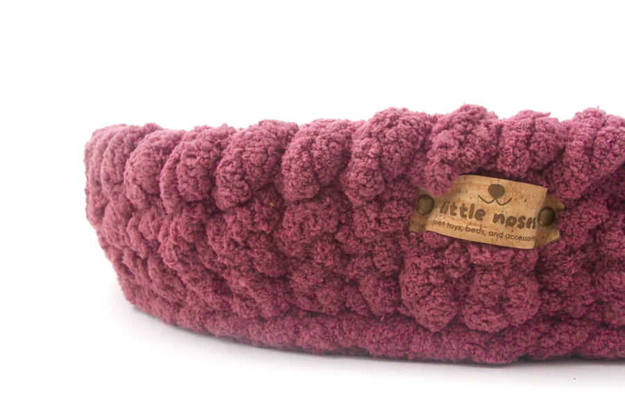 close up of dark pinkhand crocheted pet bed from little noses boutique on a white background
