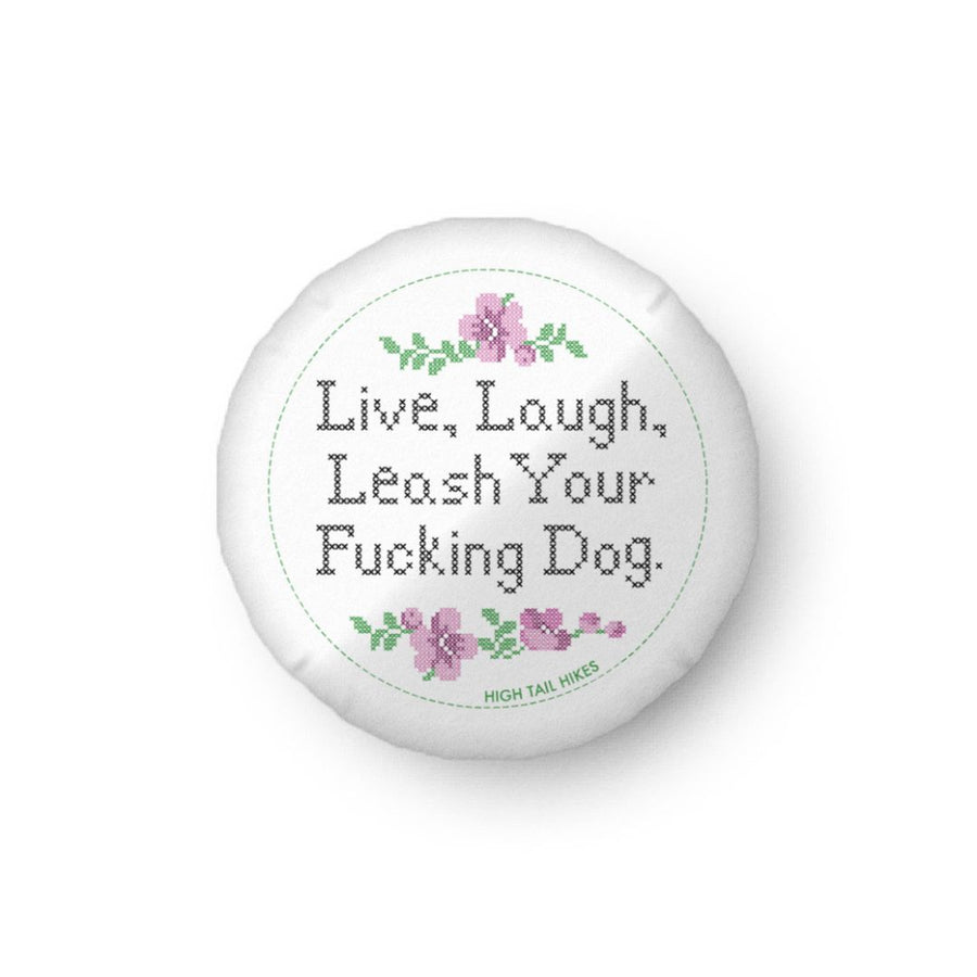 white round pillow that reads in cross stitch font "Live, Laugh, Leash Your F Dog