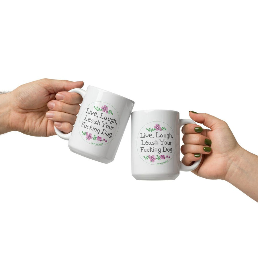 two peoples hands holding white ceramic mugs that read "live , laugh, leash your f dog"