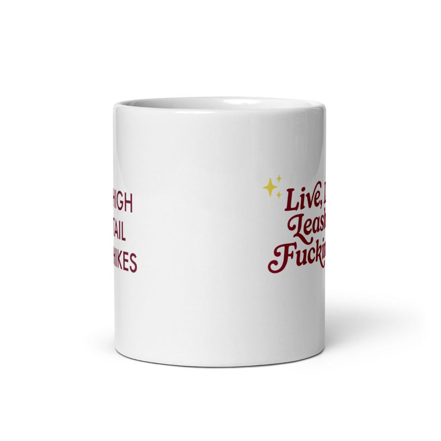 side view of 11 oz white ceramic mug, left shows red high tail hikes logo while right shows red letters that read "live, laugh, leash your f dog"