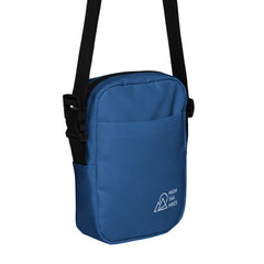 blue crossbody bag with black adjustable strap, front corner has a white high tail hikes logo on the pocket