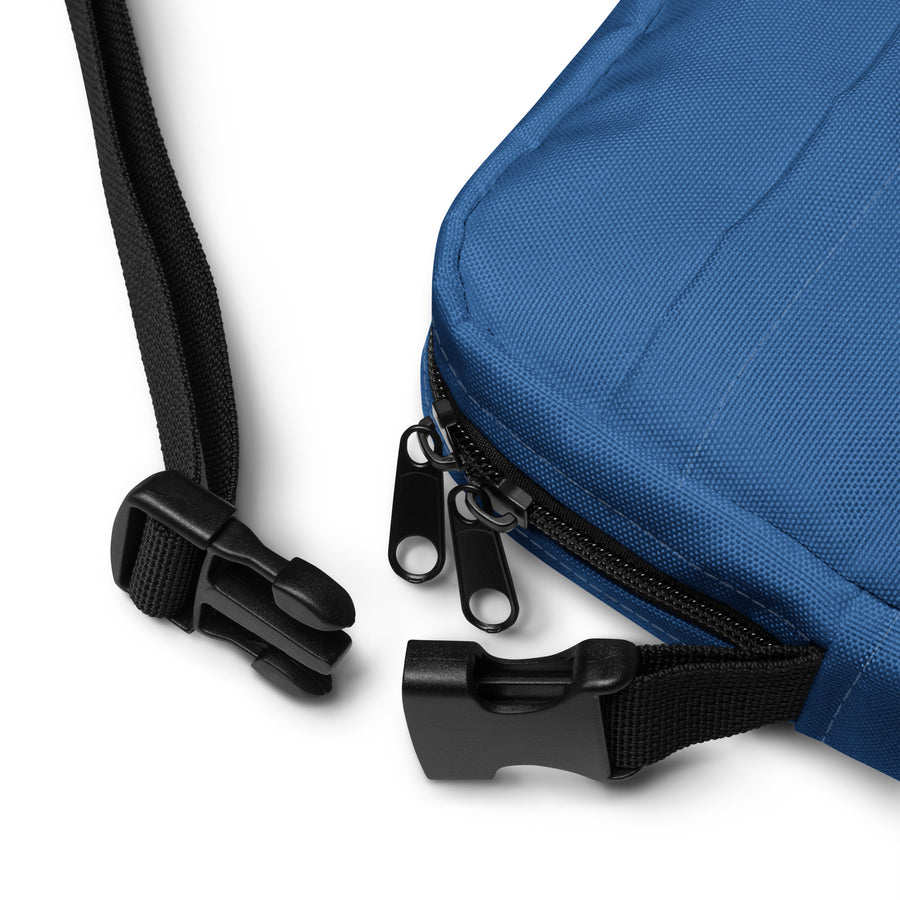 close up of blue crossbody bag showing buckle on adjustable strap and zippers