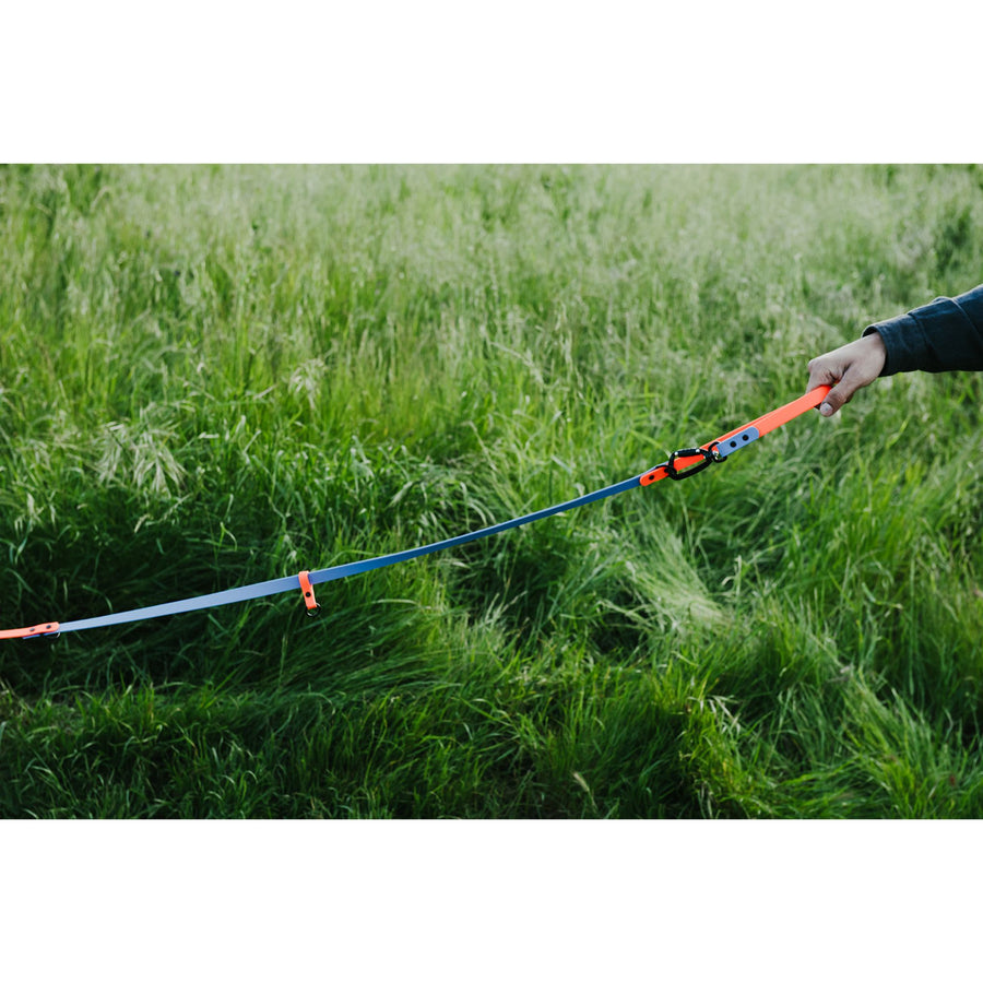 Person holding a long, colorful waterproof leash in a grassy field