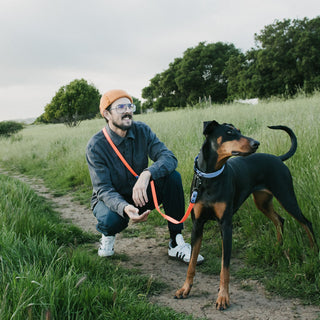 Man with a brown dog on a waterproof biothane leash in a grassy field