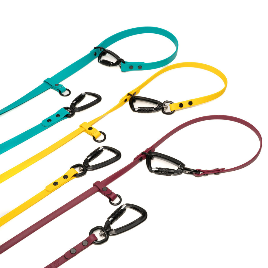 Set of three waterproof hands free dog leashes in teal, yellow, and plum with black carabiner hardware on a white background