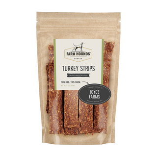 white background, tan package with jerky looking meat strips for dogs behind a clear cover, off white label that reads "Farm Hounds Treats, Turkey Strips, humanly raised by Joyce Farms"