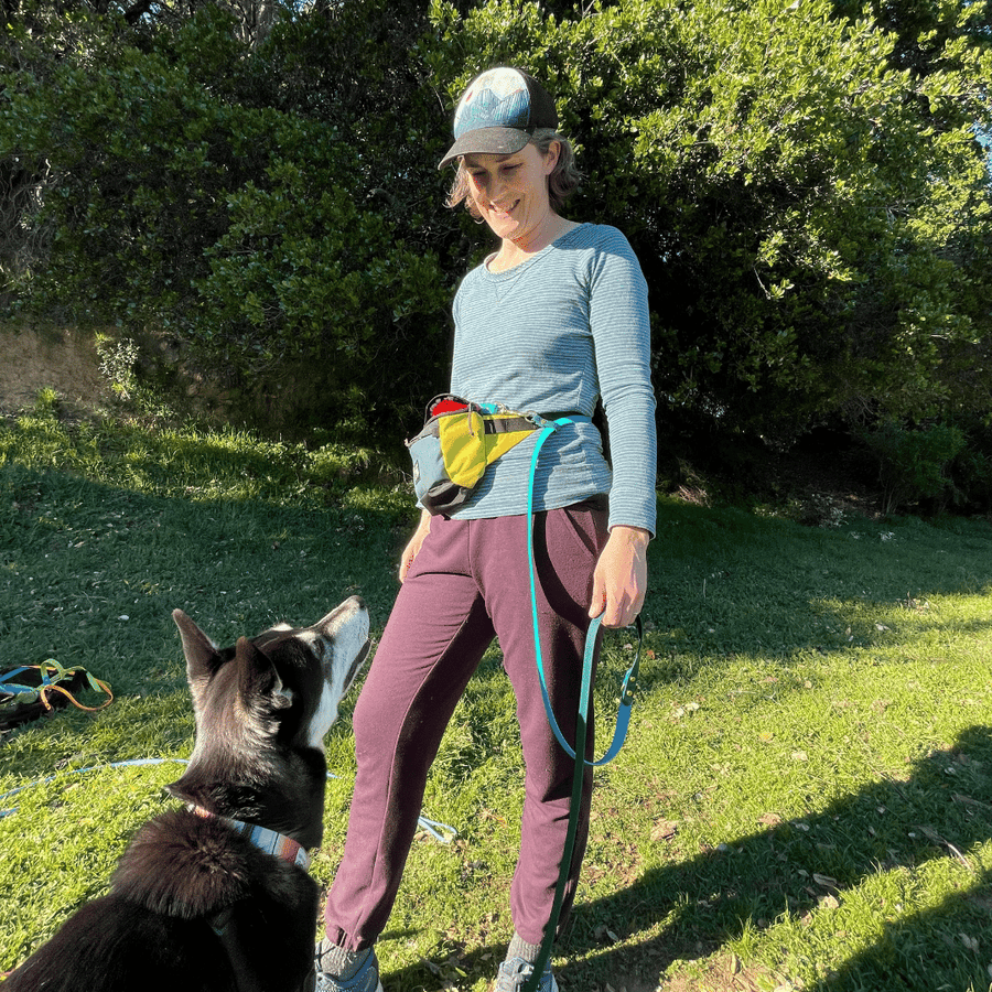 women holding the long dog leash made of biothane looking at her dog waiting for a treat