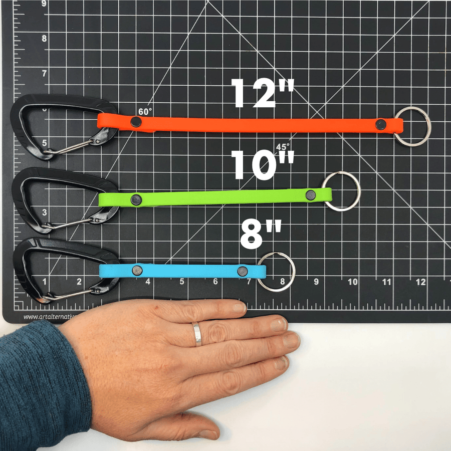 Persons hand on a ruler mat with the three sizes available of biothane clicker straps to see the size differences