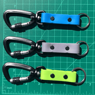 green ruler mat with three sport biothane keychains laying on top