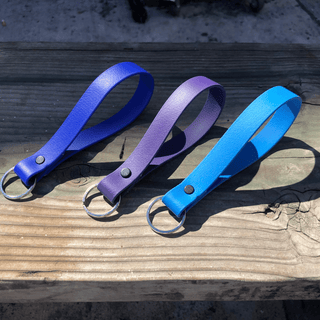 three biothane key fobs on a piece of wood