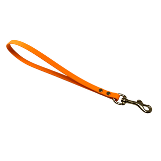 poppy colored biothane traffic handle with brass hardware on a white background