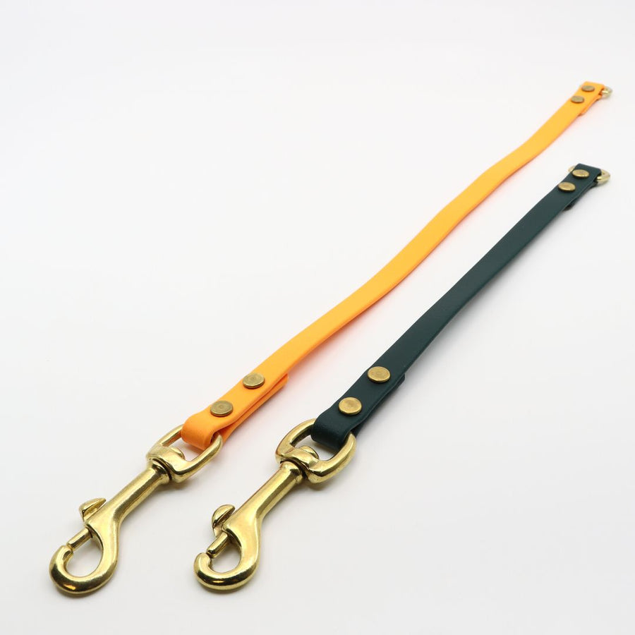 two brass biothane leash extenders with brass hardware on a white background