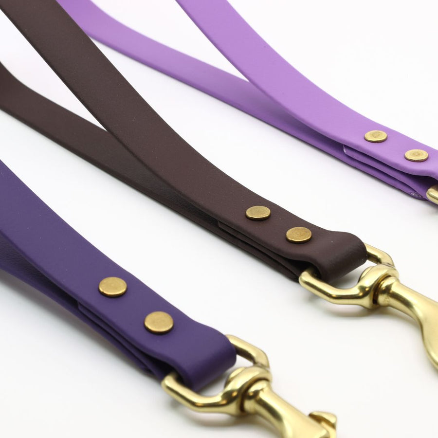 close up of the brass hardware on the biothane traffic handle in violet, lavender and plum