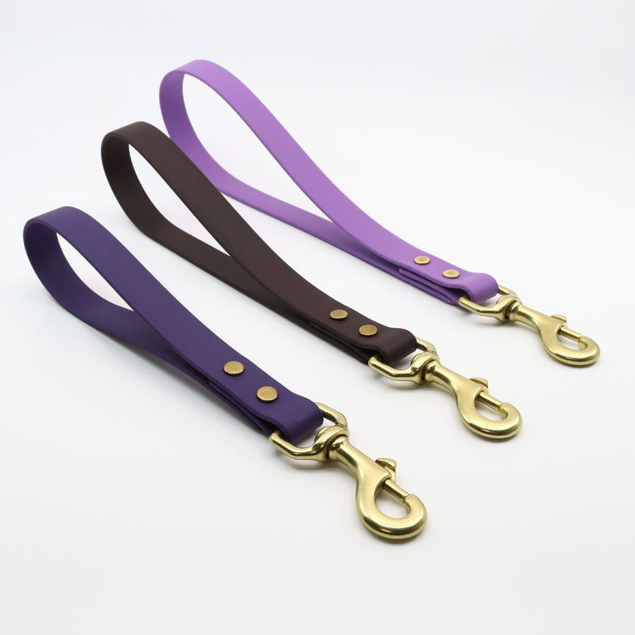 side view of biothane traffic handles with brass hardware in violet, lavender and plum