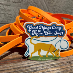 cut out sticker with a dog sniffing and wearing a biothane long leash that says "Good things come to those who sniff" sitting in front of an orange biothane long line