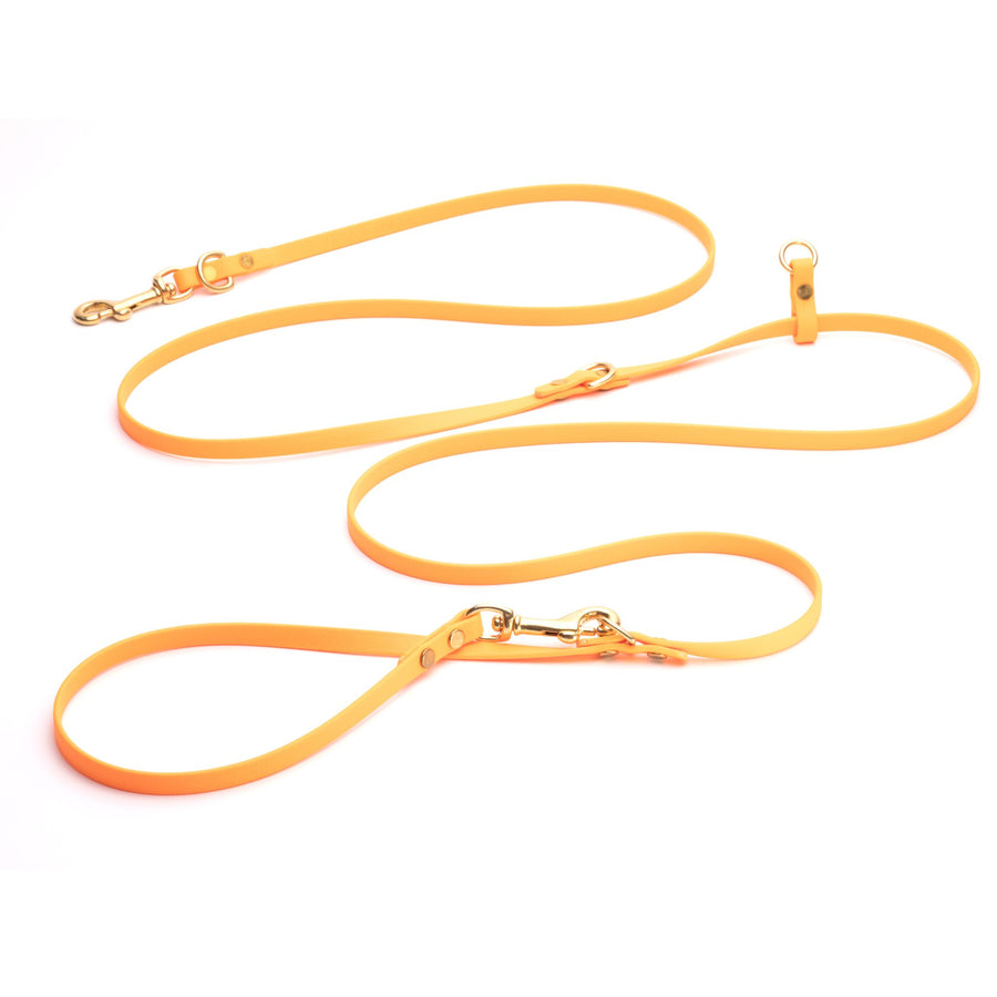 orange biothane hands free dog leash on white background with brass hardware